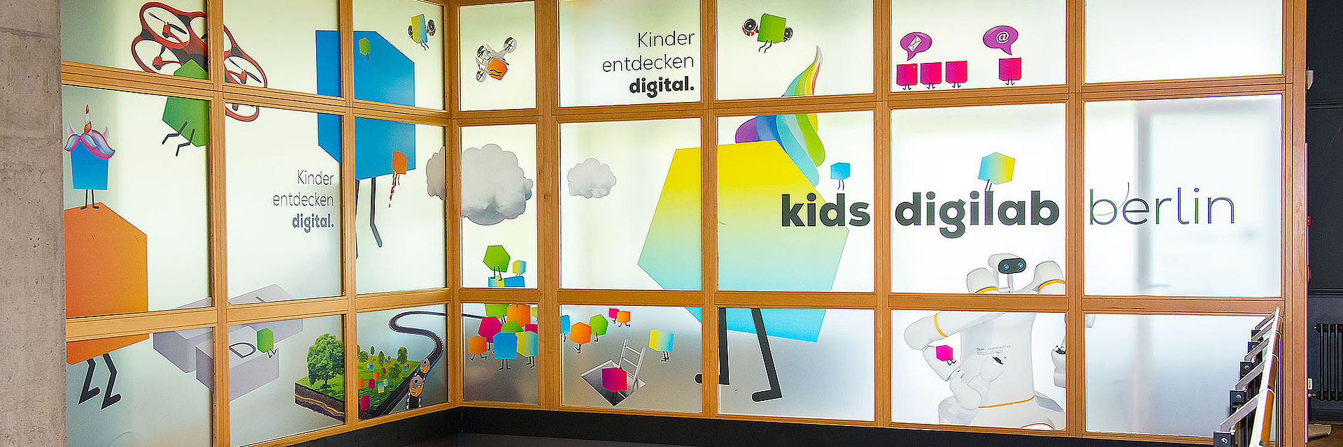 Ansicht von der Innentreppe auf Glasfassade der oberen Etage des kids.digilab und unteren Eingang des kids.digilab.