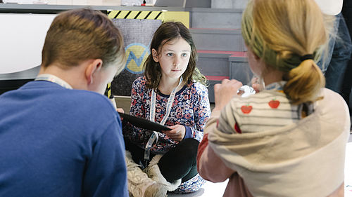 Drei Kinder im kids.digilab.berlin. Ein Mädchen hält einen Labtop.