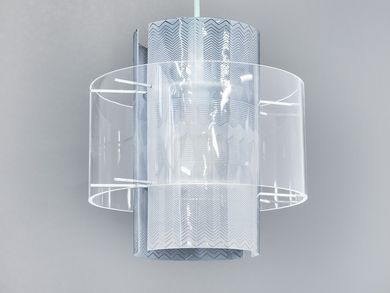 Die Lampe hängt an einem weißen Kabel. Die Glühbirne ist von durchsichtigen, rund gebogenen Plexiglasscheiben umschlossen, die mit eingravierten Zickzacklinien verziert sind.