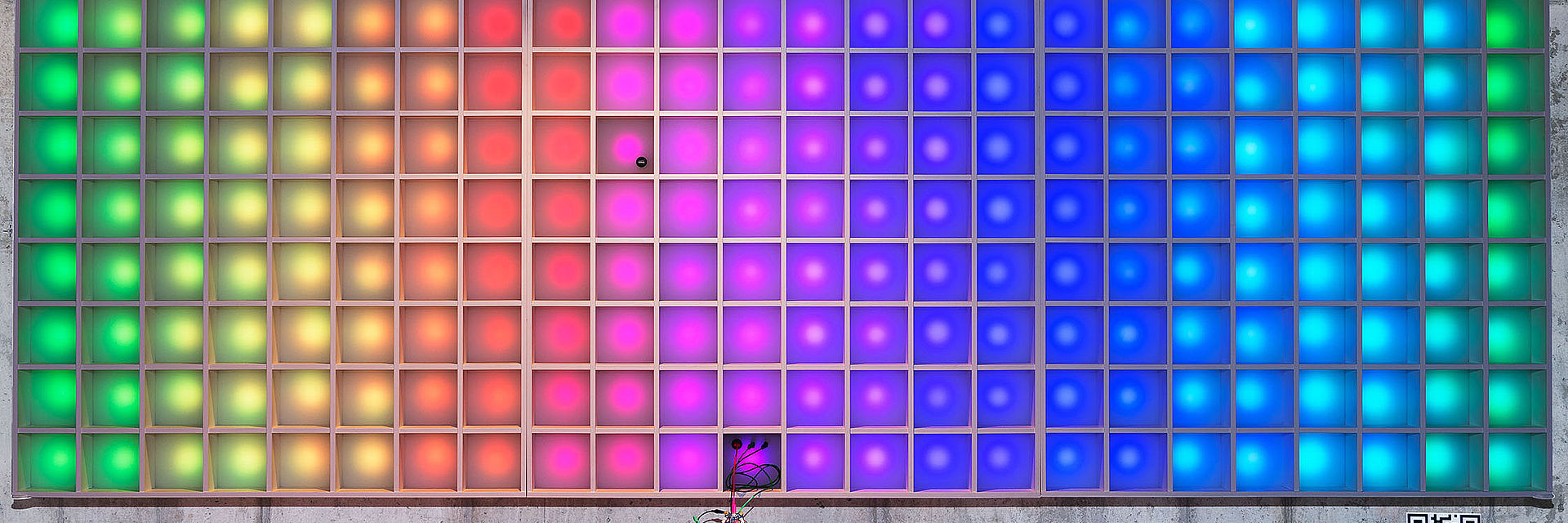 The pixel display wall is illuminated in rainbow colors.