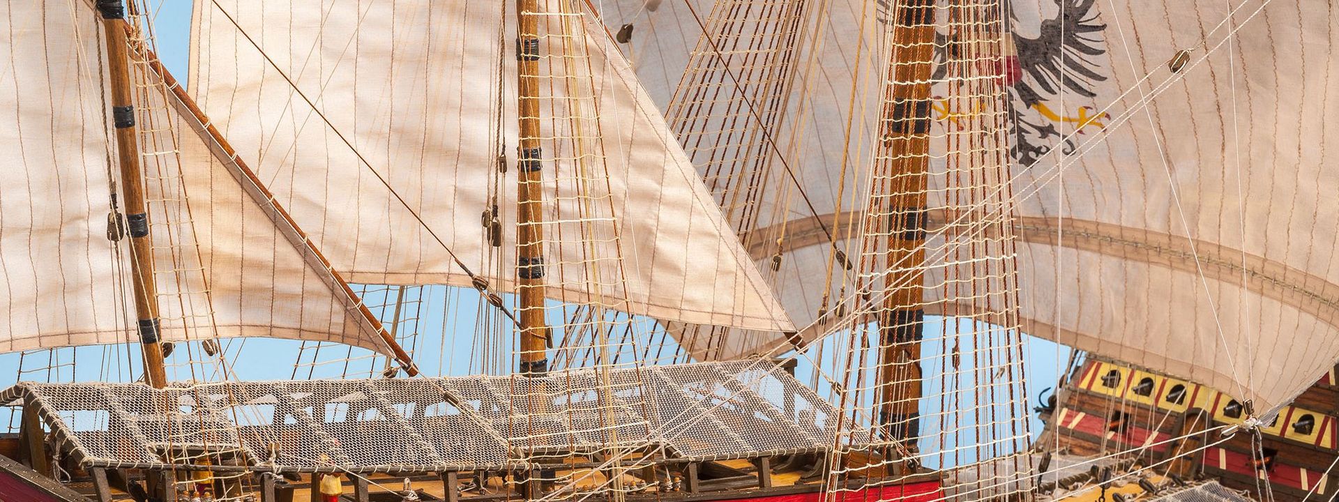 Nahaufnahme eines detailreichen Schiffsmodells mit gehissten Segeln. 