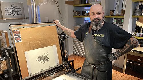 Der Museumsvorführer Stefan Krämer präsentiert den Steindruck im Ausstellungsbereich Drucktechnik.
