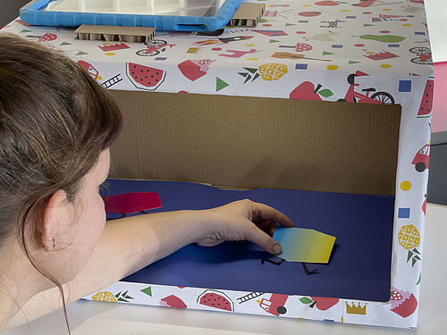 Das Foto zeigt eine Stop-Motion-Box, davor eine erwachsene Person, die etwas in der Box positioniert.
