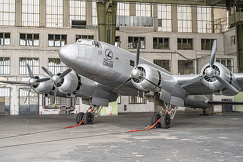 Blick vor vorne auf ein silberfarbenes Flugzeug in eine Hangar