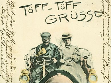 Kolorierte Ansichtskarte mit Titel „Töff-Töff Grüsse“. Fahrer und Beifahrerin auf einem Personenkraftwagen, im Kühlergrill eine Berliner Straßenszene mit Doppeldeckerbus. Der Kartenrand enthält umlaufend eine handschriftliche Mitteilung.