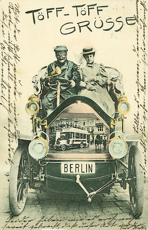 Kolorierte Ansichtskarte mit Titel „Töff-Töff Grüsse“. Fahrer und Beifahrerin auf einem Personenkraftwagen, im Kühlergrill eine Berliner Straßenszene mit Doppeldeckerbus. Der Kartenrand enthält umlaufend eine handschriftliche Mitteilung.