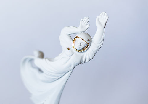 The white porcelain figure is a man floating in a cosmonaut’s suit, stretching his arms to the sky.