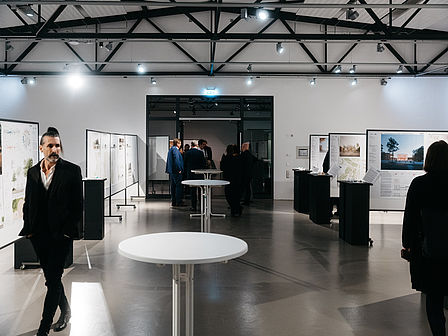 Eine Halle mit Stehtischen, an der Decke eine metallene Dachstruktur.