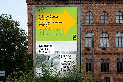 Blick auf das Science Center Spectrum mit einem Banner, das einen gelben Pfeil auf grünem Hintegrund zeigt.