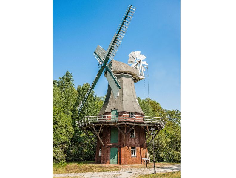 Holländermühle im Museumspark im Sommer. Die umliegenden Bäume sind leicht grün gefärbt. 