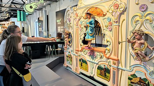 Zwei Mädchen stehen in der Dauerausstellung "Das Netz" vor einer bunten, historischen Orgel.