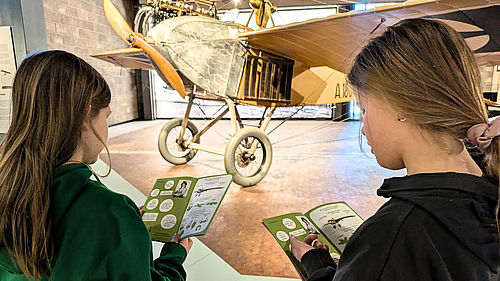 Zwei Mädchen erkunden mit dem Mitmach-Heft die Luftfahrtausstellung.