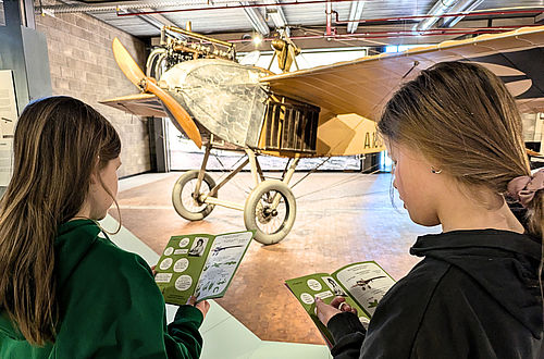 Zwei Mädchen erkunden mit dem Mitmach-Heft die Luftfahrtausstellung.