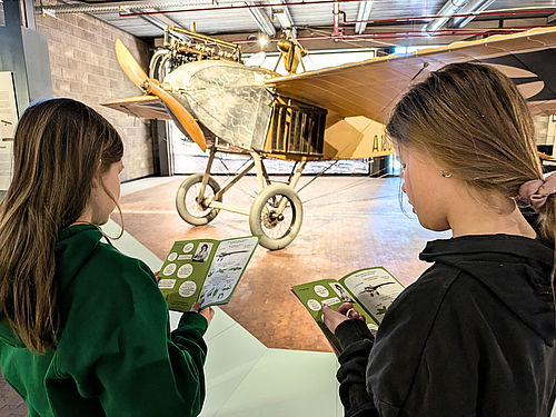 Zwei Mädchen erkunden mit dem Mitmach-Heft die Luftfahrtausstellung.