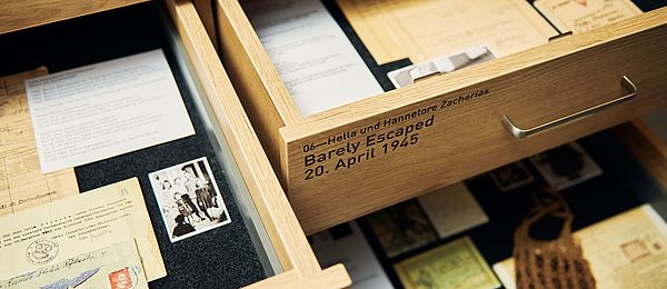 View into two opened drawers containing documents, letters and photos. On one drawer is written: Hella und Hannelore Zacharias. Barely Escaped, 20 April 1945