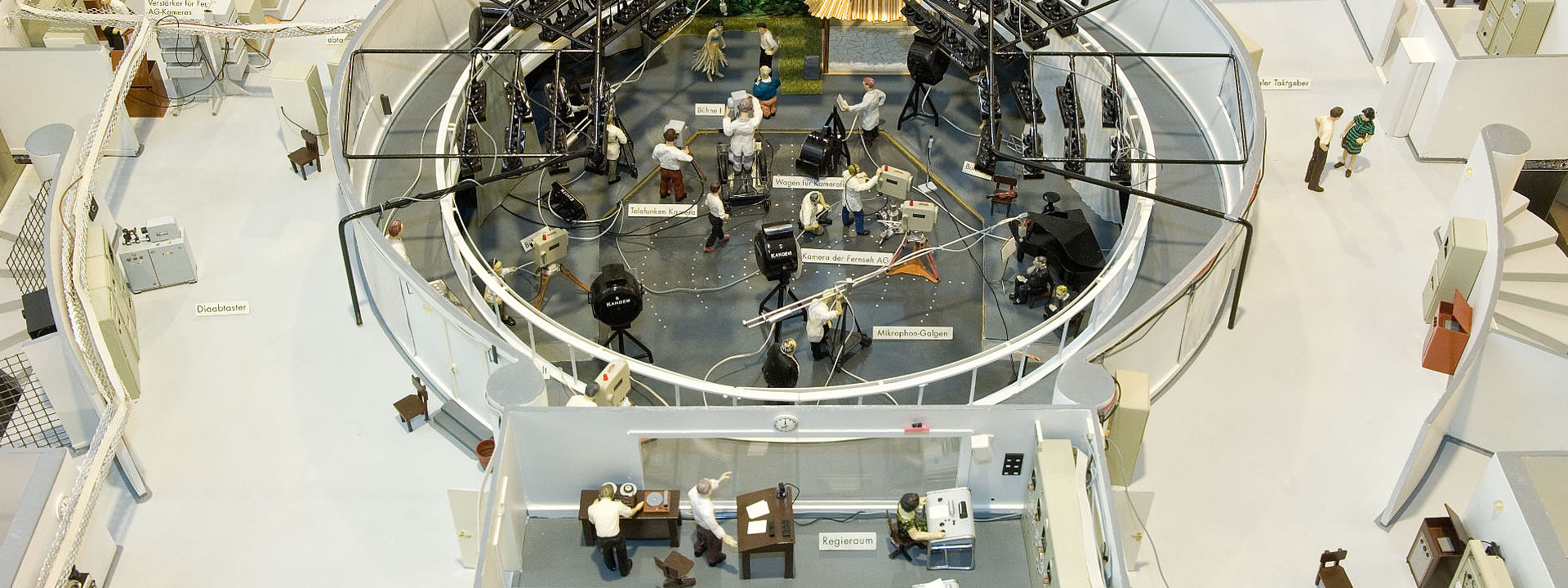 Ein kreisförmiges Fernsehstudio, das in zwei Ebenen geteilt ist. Unten befindet sich das Studio mit Bühne. Oben der Regieraum.