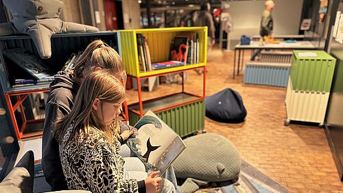 Zwei Kinder schauen sich auf der Mitmachinsel in der Schifffahrtsausstellung im Deutschen Technikmuseum ein Buch an.