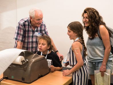 Ein älterer Mann erklärt drei jungen Frauen die Funktion eines Fernschreiber-Gerätes. Eine typische Situation bei der Langen Nacht der Museen, bei der auch Mitglieder des Fördervereins aktiv sind.