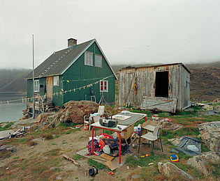 Ein grünes Haus in Grönland, daneben ein einfacher Schuppen.