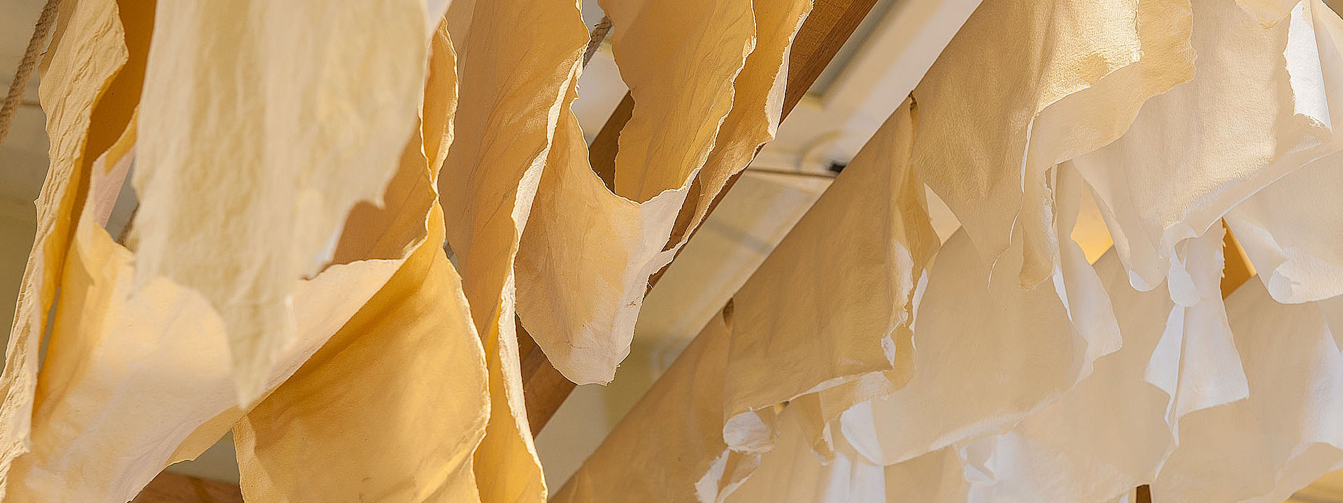Handegschöpftes Papier wird zum Trocknen aufgehängt.