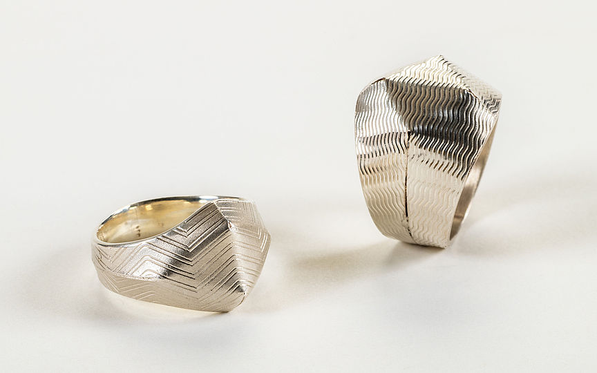 Zwei silberne Ringe. Links mit eingravierten Wellenmuster und rechts mit Zickzack-Muster.