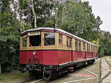 Foto einer gelb-roten S-Bahn auf Schienen in einem Park.