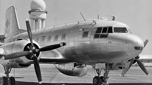 Schwarzweiss-Foto: Blick auf ein Flugzeug des Typs Iljuschin IL-14P in restauriertem Zustand.