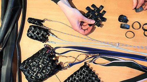 Auf einem Tisch liegen alte Fahrradschläuche. Aus zugeschnittenen Schlaufen und einer Kordel entstehen geflochtene Taschen in verschiedenen Größen.