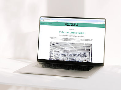 Ein Foto eines Laptops auf dem die Startsete des Digitalen Magazins des Deutschen Technikmuseums geöffnet ist. Man sieht ein schönes grün-weißes Layout und den Schriftzug "Mensch! Technik!