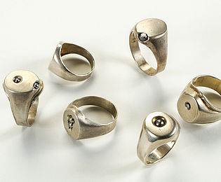Sechs silberne Siegelringe, in deren Oberfläche kleine Stahlkugeln gedrückt wurden.
