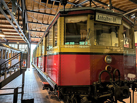Foto eines gelb-roten S-Bahn-Wagens in einem Lokschuppen.