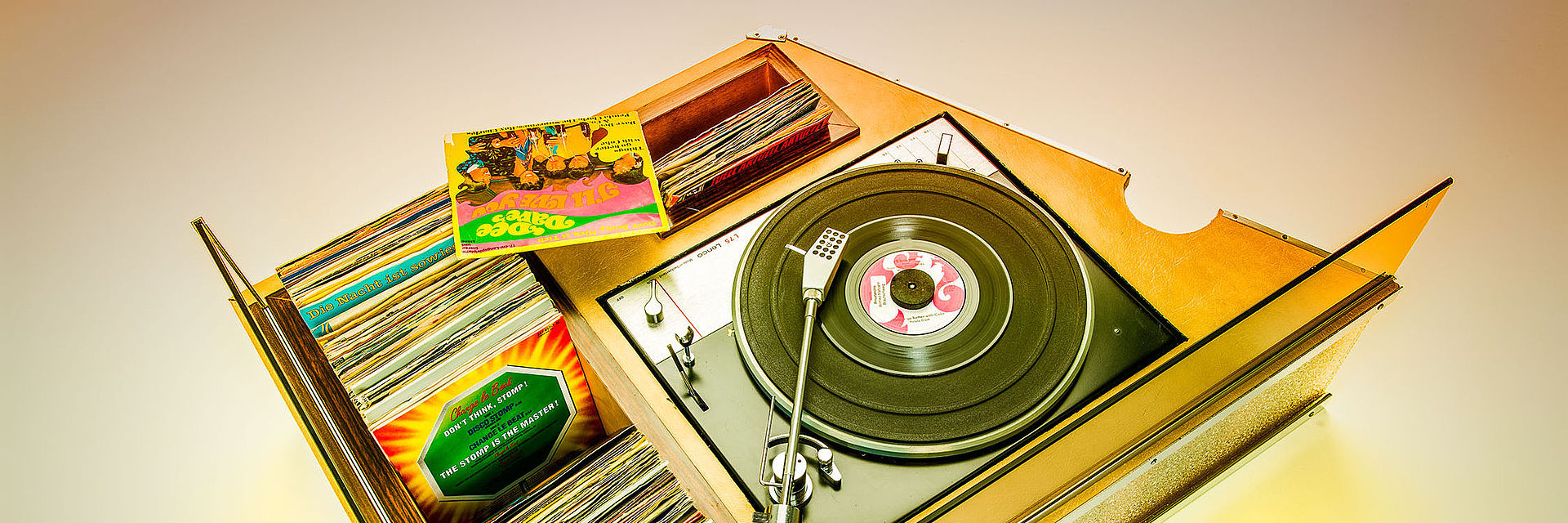 Der Plattenspieler L75 der Firma Lenco, verbaut in einem Teil der selbstgebauten DJ-Anlage von Winfred „Fredi“ Maltzahn. In das furnierte Pult sind Fächer eingelassen, in denen sich Single-Schallplatten befinden. 