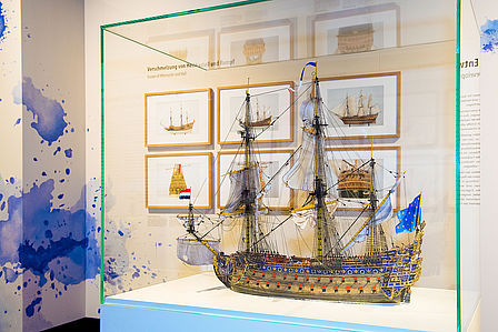 Im Vordergrund eine Vitrine mit einem Model des Barockschiffes LE SOLEIL ROYAL, im Hintergund gerahmte Schiffszeichnungen.