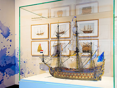 Im Vordergrund eine Vitrine mit einem Model des Barockschiffes LE SOLEIL ROYAL, im Hintergund gerahmte Schiffszeichnungen.