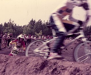 Eine Gruppe von Jungen fährt auf einem sandigen Gelände rasant mit BMX-Rädern.