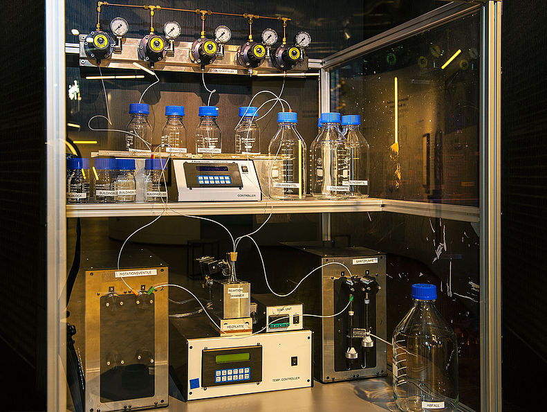 Der Oligosaccharid-Synthesizer ist in einen Laborschrank eingebaut. Auf zwei Ebenen stehen Messgeräte und Flaschen, die über Schläuche mit einem Ventilsystem verbunden sind.