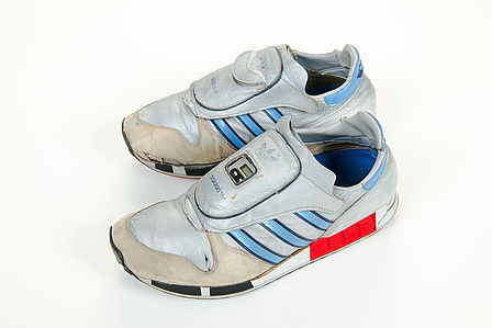 Ein Paar silber-graue Turnschuhe. Auf dem Schuh im Bildvordergrund ist ein kleiner Computerchip zu erkennen.