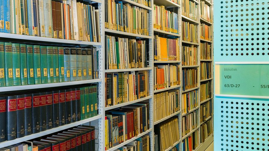 Metallregal, in dem mit Signaturen versehene Bücher geordnet in Reihen stehen. 