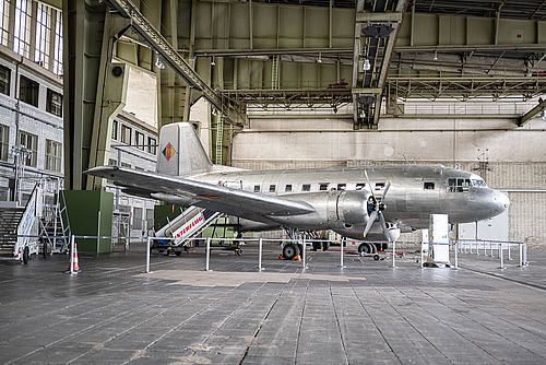 Ein silberfarbenes Flugzeug steht in einem Hangar.